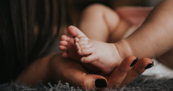 baby's feet with mom's hands